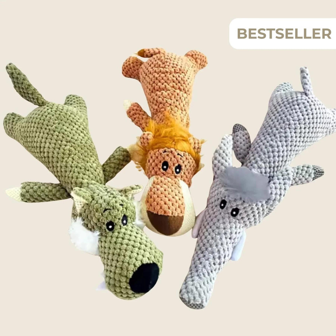 Drei gestrickt wirkende Plüschtiere in Grün, Orange und Grau liegen nebeneinander auf beigem Hintergrund und zeigen Wolf, Löwe und Elefant. 1