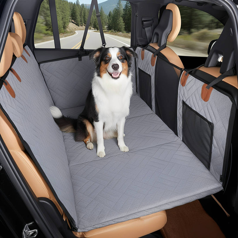 Border-Collie-Mischling sitzt auf der grauen, gesteppten Rücksitzverlängerung im Auto, während draußen eine Straße vorbeizieht. 11